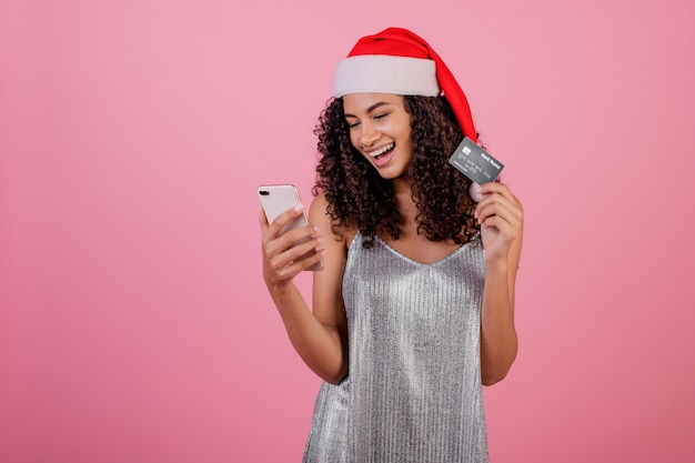 Piękna uśmiechnięta murzynka jest ubranym Santa kapelusz z telefonem i kredytową kartą