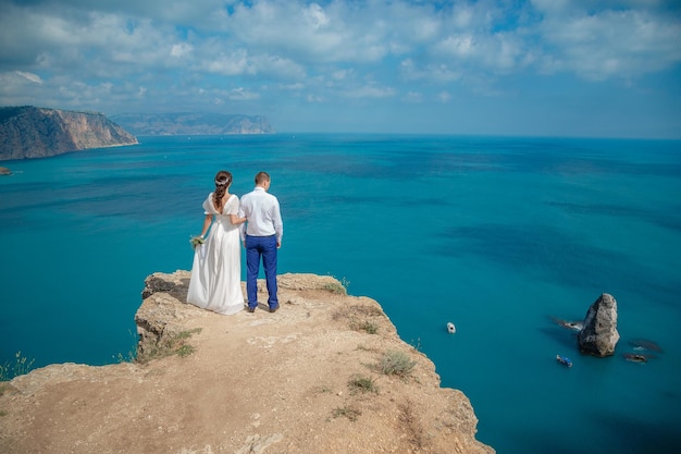 Piękna uśmiechnięta panna młoda i pan młody spacerujący po plaży, całujący się i bawiący się ceremonia ślubna w pobliżu skał i morza Ceremonia ślubna na wybrzeżu Cypru