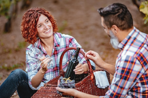 Piękna uśmiechnięta para bawi się i degustuje wino w winnicy.