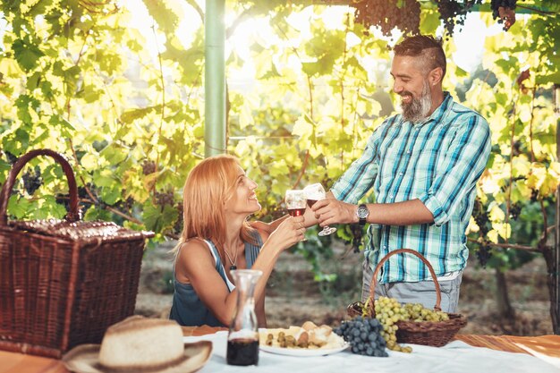 Piękna uśmiechnięta para na pikniku i degustacji wina w winnicy.