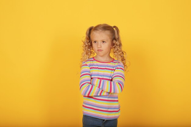 piękna uśmiechnięta szczęśliwa blondynka na żółtym tle w kolorowej kurtce