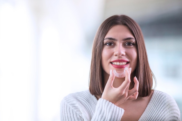 Piękna uśmiechnięta Turczynka trzyma naramiennik invisalign z miejscem na kopię