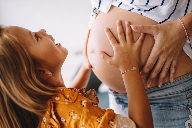 Zdjęcie piękna w ciąży kobieta z uroczą córką w ciąży koncepcja miłości rodzinnej