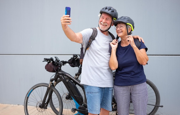 Piękna Wesoła Para Starszych Biorąca Selfie Podczas Uprawiania Sportu Z Rowerami Elektrycznymi, Zdrowy Styl życia Na Emeryturze I Koncepcja Zrównoważonej Mobilności