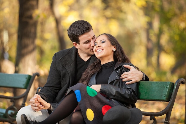 Piękna zakochana para siedzi na ławce w jesiennym parku
