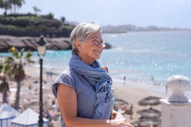 Piękna zrelaksowana starsza kobieta odpoczywa w słoneczny dzień w pobliżu plaży Uśmiechnięta starsza pani ciesząca się wakacjami na morzu