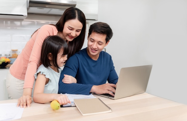 Zdjęcie piękne azjatki urocza dziewczyna patrząc na ekran laptopa przystojni mężczyźni pracujący online na biurku w domu to nowe normalne życie dla rodziny.