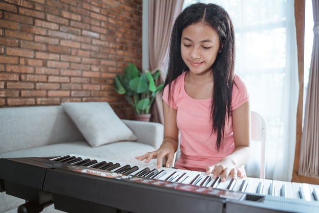 Piękne azjatyckie dziewczyny nastolatka gra na instrumencie fortepianowym