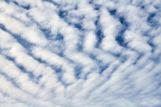 Piękne błękitne niebo z niezwykłymi białymi chmurami Altocumulus undulatus, niezwykła formacja chmur. Białe chmury cirrocumulus, zachmurzone niebo altocumulus, tekstura chmur stratocumulus, tło błękitnego nieba