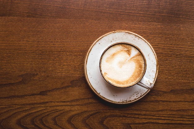 Piękne cappuccino ze sztuką w białej filiżance. Widok z góry, z bliska.