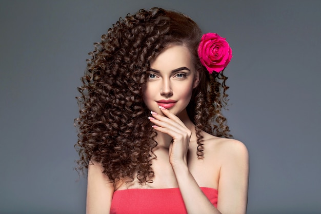 Piękne curly włosy kobieta na czerwono z czerwonymi ustami i manicure sukienka, piękna czerwona fryzura afro. Strzał studio.
