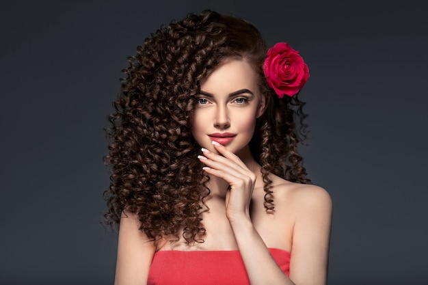 Piękne curly włosy kobieta na czerwono z czerwonymi ustami i manicure sukienka, piękna czerwona fryzura afro. Strzał studio.