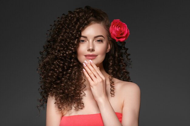 Piękne curly włosy kobieta na czerwono z czerwonymi ustami i manicure sukienka, piękna czerwona fryzura afro. Strzał studio.