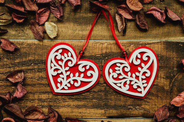 Zdjęcie piękne drewniane serca z czerwonymi suchymi płatkami wokół