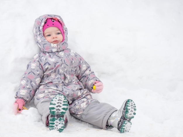 Piękne dwuletnie dziecko jest zmęczone i odpoczywa w śnieżnej przestrzeni kopii