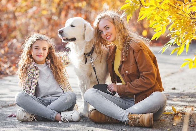 Piękne dziewczyny z golden retriever. Dwie siostry na zewnątrz zabawy fun.pet właścicieli jesienią.