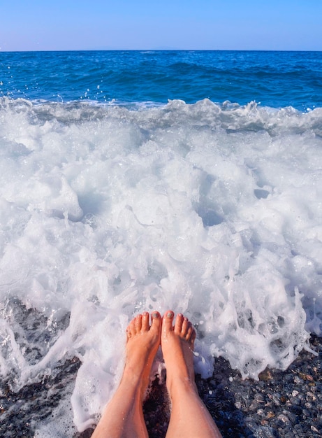 Piękne kobiece nogi w pianie wody morskiej na Morzu Egejskim w słoneczny dzień w Grecji