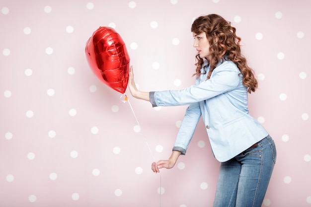 Zdjęcie piękne kręcone kobiety z balonami w kształcie serca na walentynki