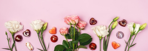 Piękne kwiaty tło z czekoladowymi cukierkami Wiosna w tle Białe i różowe kwiaty na różowym tle Długie różowe róże i Eustoma