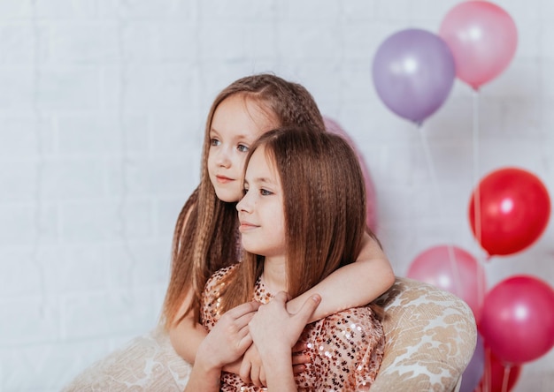 Piękne małe siostry dziewczyny żartują na przyjęciu urodzinowym młode panie z balonami przygotowują się do świątecznego