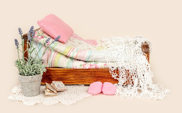 Piękne meble do łóżka do sesji noworodkowej z dekoracją w fioletowe kwiaty, różową poduszką i kocami. Małe zaprojektowane miejsce na zdjęcie niemowlęcia na białym tle