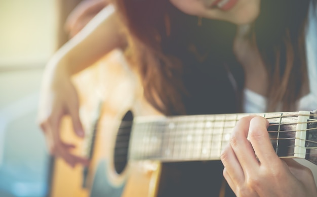 Piękne młode kobiety ćwiczą używać palca do grania na gitarze.