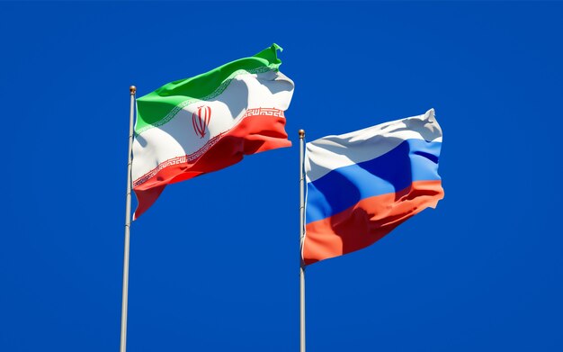 Piękne narodowe flagi państwowe Iranu i Rosji razem na błękitnym niebie. Grafika 3D