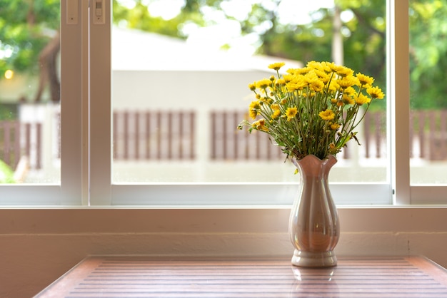 Zdjęcie piękne naturalne żółte kwiaty w wazonie umieścić na stole ze światłem z okna.