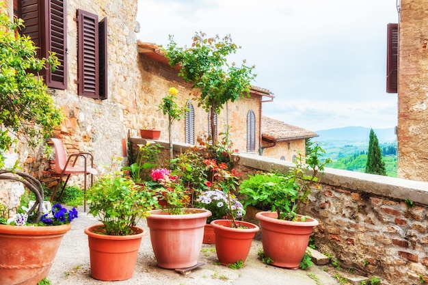 Piękne patio z kwiatami średniowiecznego budynku. San Gimignano, Toskania, Włochy