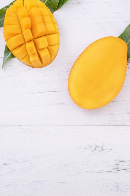 Piękne posiekane dojrzałe mango z zielonymi liśćmi na jasnym białym kolorze drewnianym tle widok z góry płaska położona kopia przestrzeń Koncepcja projektowania owoców tropikalnych