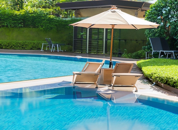 Piękne puste krzesło z parasolem wokół odkrytego basenu w kurorcie hotelowym na wakacje