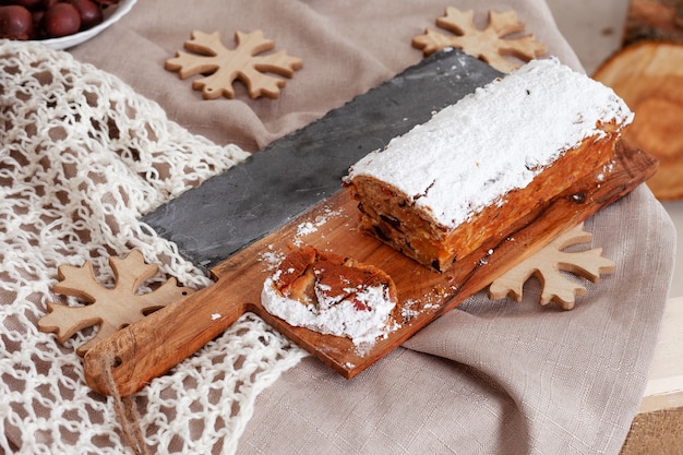 Zdjęcie piękne pyszne domowe świąteczne ciasto z suszonymi owocami na drewnianej desce z dekoracjami z okazji świąt bożego narodzenia