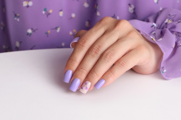 Piękne ręce kobiece z fioletowym manicure paznokci kwiatowy projekt