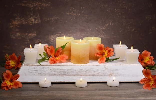 Piękne świece z kwiatami na stole na brązowym tle