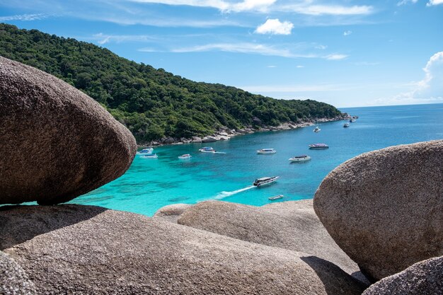 Piękne tropikalne morze z ułożonymi dużymi kamieniami i turystami podróżującymi łodzią motorową na wyspie Similan