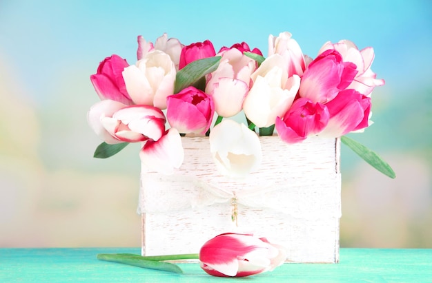 Piękne tulipany w drewnianym pudełku, na jasnym tle