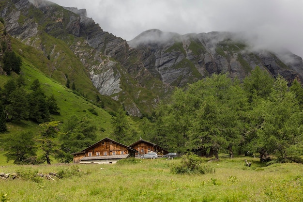 Piękne tyrolskie domy otoczone skalistymi górami we mgle w austriackich Alpach w pobliżu szczytu skalnego Grossglockner Kals am Grossglockner Austria