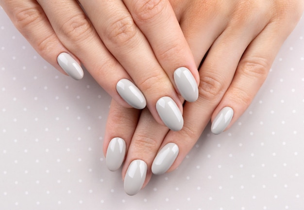 Piękne womans ręce z manicure z bliska na tle kropki