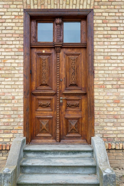 Piękne zabytkowe drewniane drzwi z rzeźbionymi elementami dekoracyjnymi na starym zabytkowym budynku Projekt wnętrz architektury XIX wieku