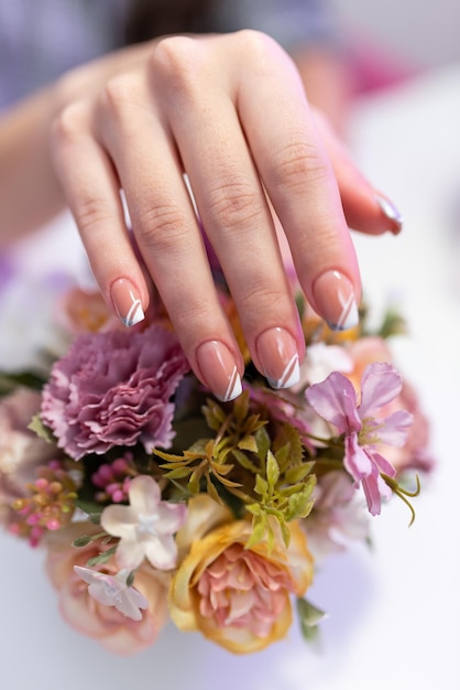 Piękne zadbane kobiece dłonie z pięknym manicure na bukiecie kwiatów Koncepcja salonu piękności manicure pedicure Pielęgnacja paznokci Zabieg kosmetyczny