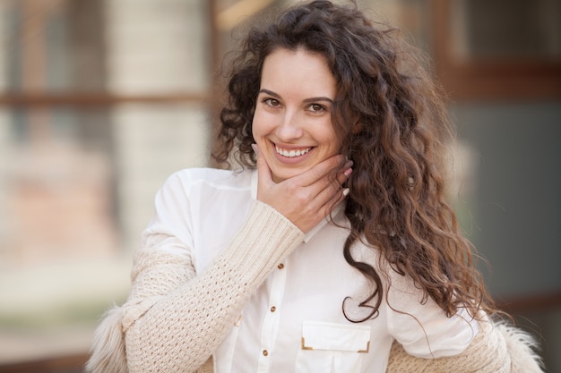 Pięknej brunetki kędzierzawa kobieta ono uśmiecha się outdoors