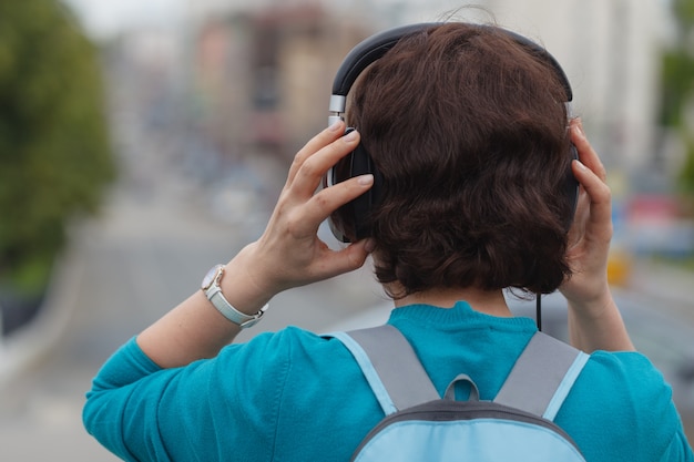 Pięknej brunetki kobiety słuchająca muzyka z hełmofonami w mieście