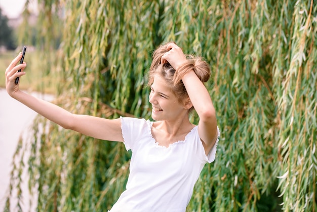 Pięknej Młodej Blondynki Kaukaska Kobieta Z Kawą Na Wynos Bierze Selfie Z Smartphone Outdoors W Parku W Jesieni.