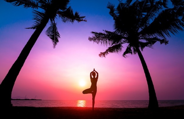 Pięknej młodej kobiety praktyczny joga przy plażą. Ćwiczenia wcześnie rano. wschód słońca