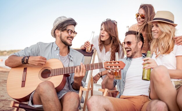 Piękni młodzi ludzie z gitarą bawią się na plaży