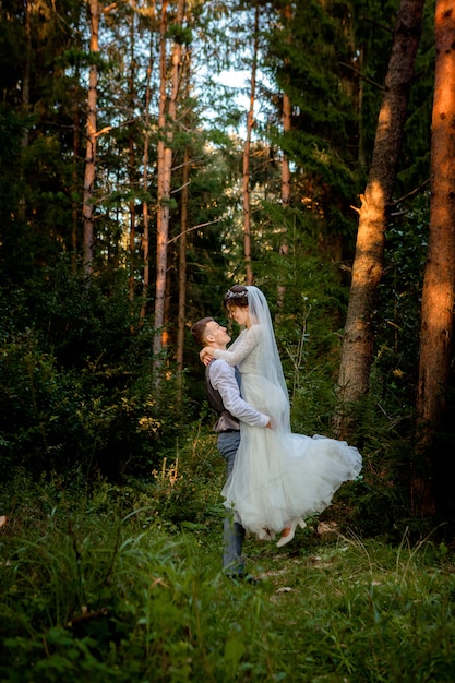 Piękni nowożeńcy pary odprowadzenie w lesie. Nowożeńcy. Panny młodej i pana młodego, trzymając rękę w lesie sosnowym, zdjęcie na Walentynki