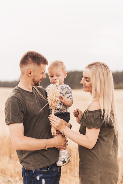 Zdjęcie piękni rodzice rodziny i młody syn w polu pszenicy. mama, tata i dziecko razem. szczęśliwa rodzina, rodzice przytulają swojego synka