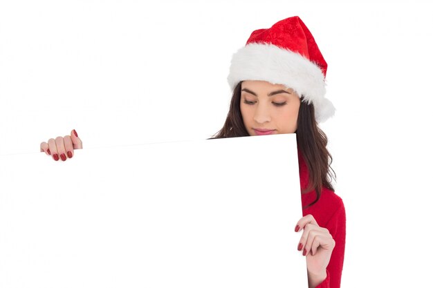 Piękno brunetka w Santa kapeluszu pokazuje białego plakat