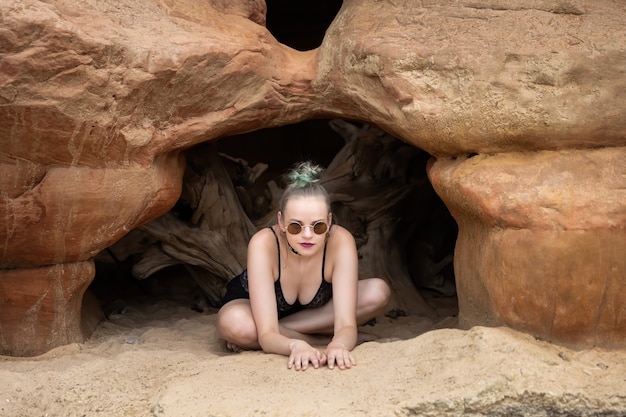 Piękno i zdrowy styl życia. Młoda kobieta w czarnej bieliźnie pozowanie w pobliżu jaskiń z piaskowca nad brzegiem morza. Jaskinie z muszli skalnych.