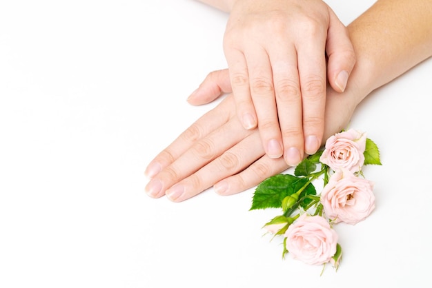 Piękno kobiety ręka z kwiatami róży leży na białym tle stołu